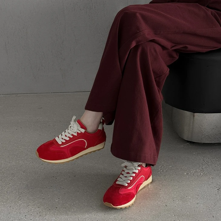 Red suede low top trainer sneakers worn with wide leg trousers