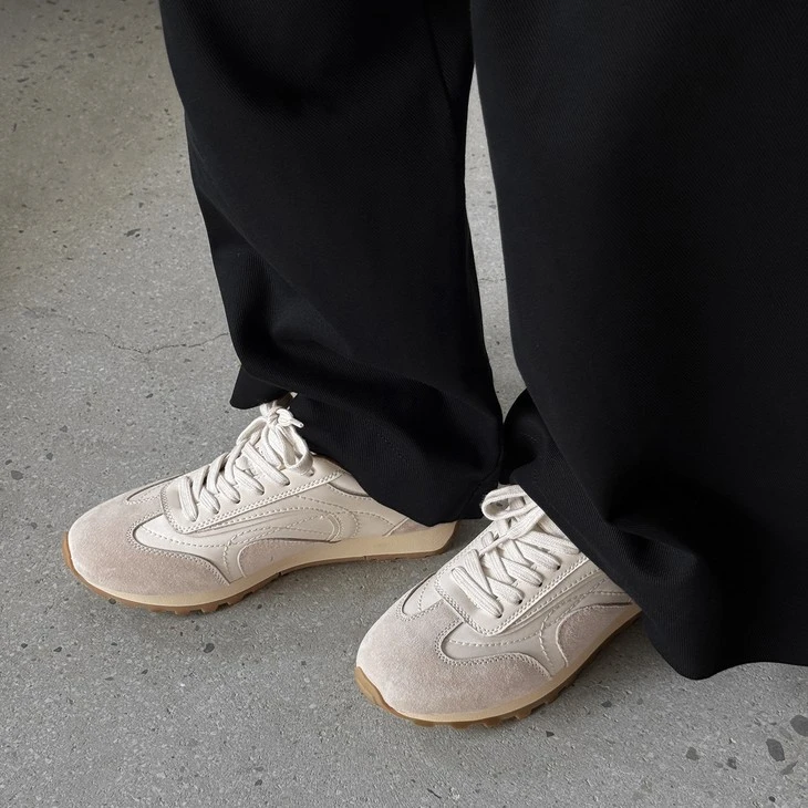 Off-white suede low top sneakers worn with black trousers